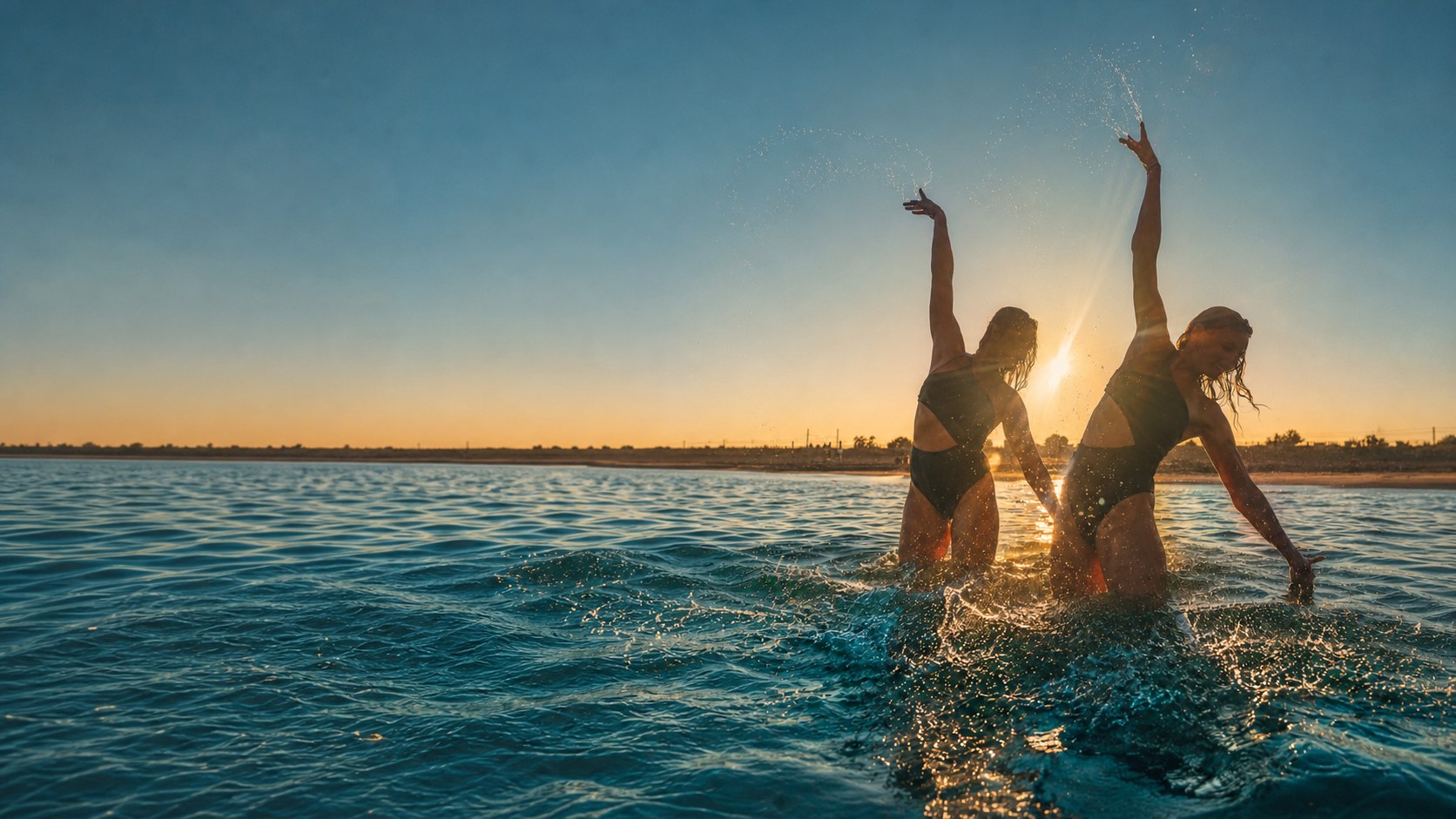 May et Victoria à contre-jour dans les gerbes d'eau au soleil couchant, à Sète